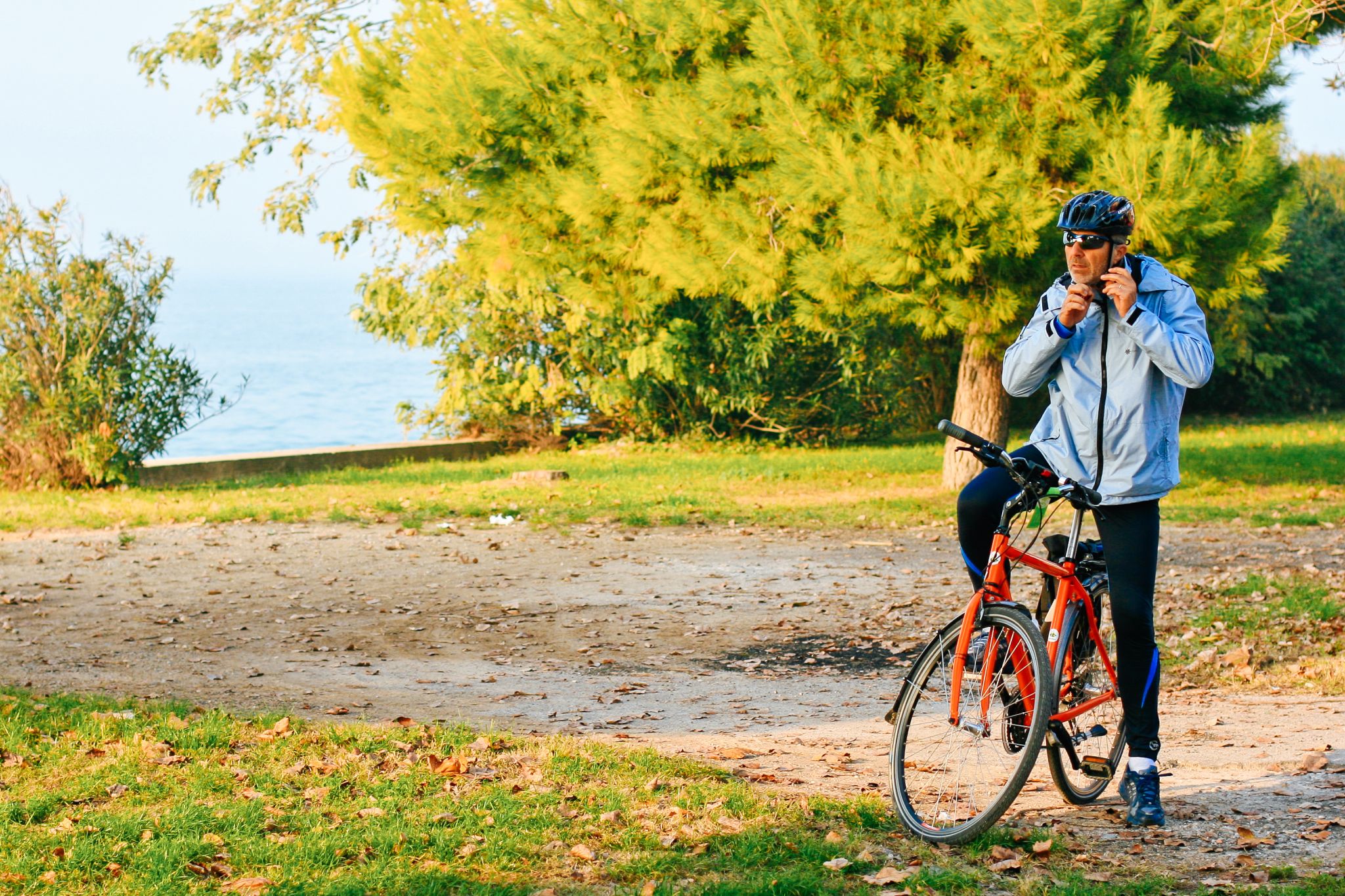 Cicloturista fermo intento ad allacciarsi il caschetto, bici muscolare Girolibero, turismo slow, tra Venezia e Parenzo